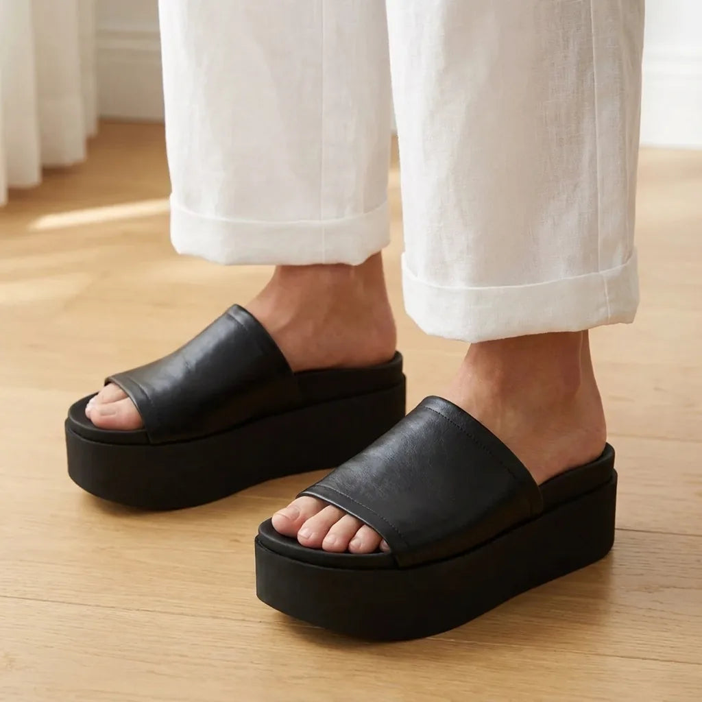 Mujer con pantalon blanco luciendo las sandalias Arwinn negras